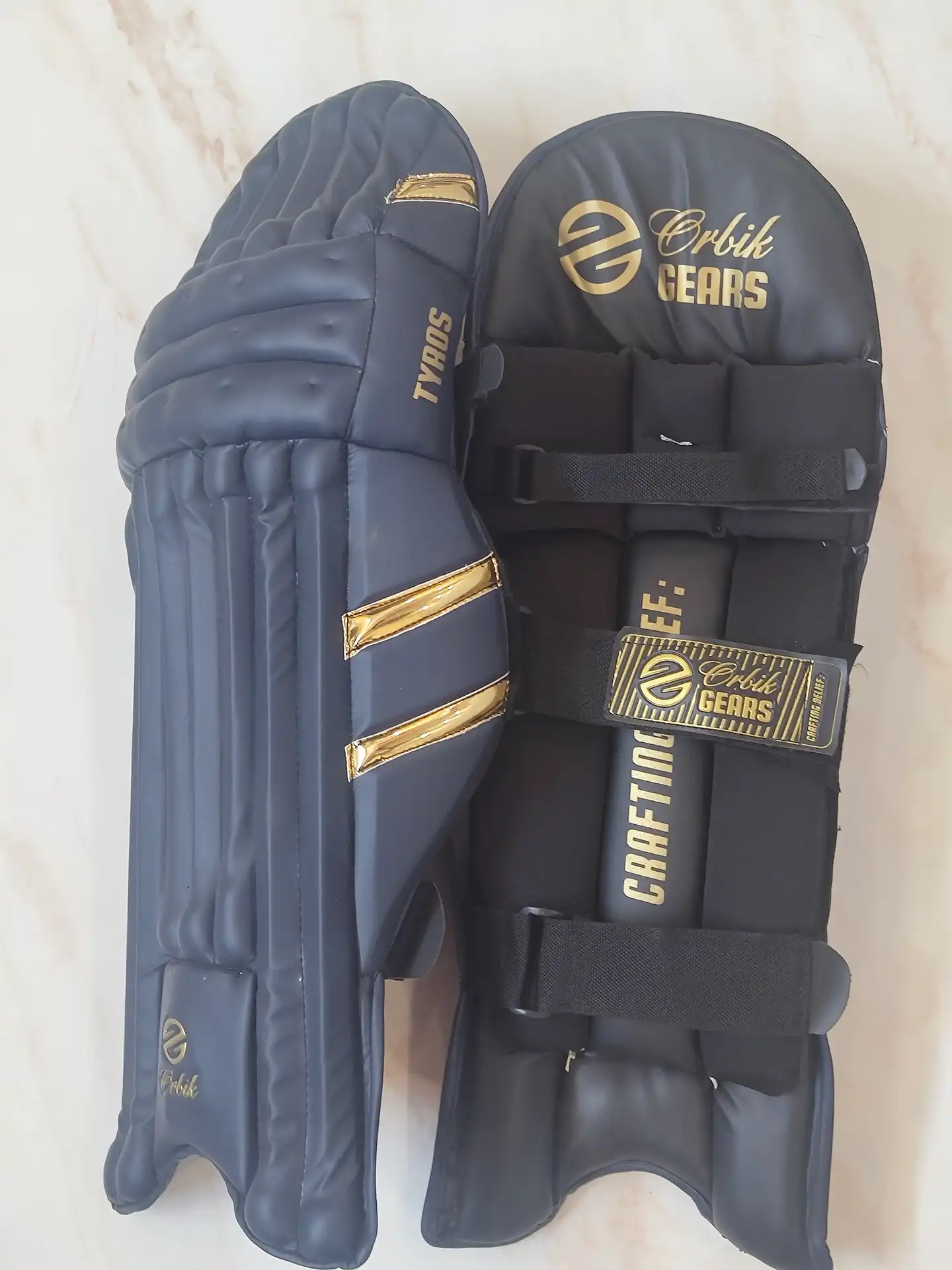 Tyros cricket batting pads side view showing protective padding and gold detailing